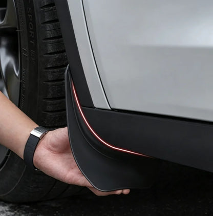 Hand showing a mud flap installed on a Model Y